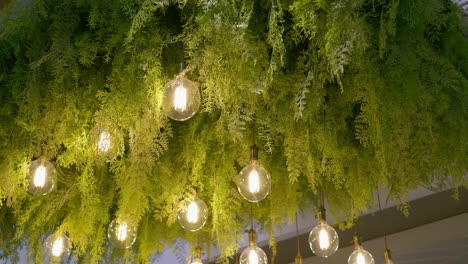 Dekorative-Glühlampen-Als-Beleuchtungskörper-Und-Einige-Grüne-Fichten-Dienen-Als-Ornamente-Zur-Verschönerung-Der-Decke-Einer-Halle-In-Bangkok,-Thailand