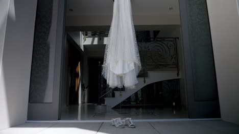 Ein-Brautkleid-Und-Ihre-Schuhe-Hängen-Am-Eingang-Eines-Luxuriösen-Hauses,-Die-Hochzeit-Wird-Vorbereitet
