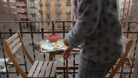 Frau-Im-Pyjama-Hinterlässt-Leckere-Frühstücks-Arepas-Auf-Dem-Balkontisch-Am-Wintertag,-Kein-Gesicht