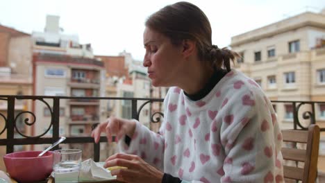 Cozy-Balcony-Woman-in-pajamas-Enjoying-Arepas-homemade-breakfast-Wide-Shot
