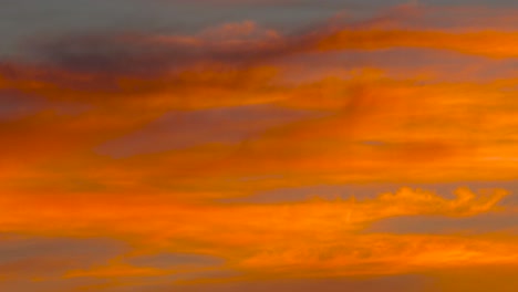 Slow-zoom-in-into-deep-orange-cloud-formation-during-colorful-sunset,-Latvia