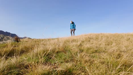 Male-Hiker-Walking-Across-Wild-Meadow-Valley-Ridge-In-Valmalenco-Alps