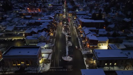 Aerial-reveal-of-town-square-covered-in-snow-during-colorful-winter-sunset