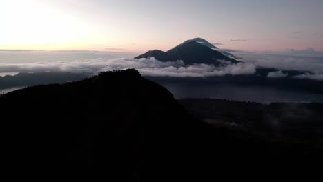Mount-Batur-Surrounded-With-Clouds-At-Sunrise-In-Bali,-Indonesia---Aerial-Drone-Shot