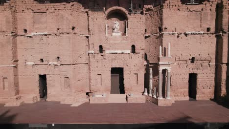 Drone-elevation-to-contemplate-the-magnificent-ancient-wall-in-the-south-of-France,-it-has-an-earthy-color-with-its-old-Roman-columns-and-its-statue-of-Apollo