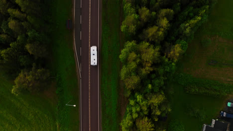 Top-down-drone-shot-above-a-RV-driving-on-a-asphalt-road,-summer-evening-in-Lapland