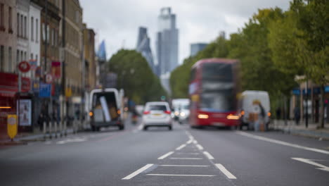 Time-lapse-of-London-street-traffic-heading-in-and-out-of-the-city-with-out-of-focus-using-depth-of-field-focus-on-the-close-foreground-with-skyscrapers-in-the-background