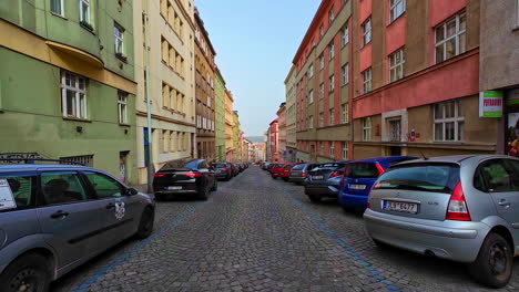 Prague-street-with-cars-parked-along-cobbled-lanes-flanked-by-colorful-buildings