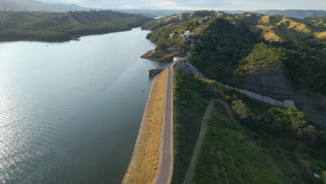 Drone-flight-over-dam-with-road-of-lake-in-Santiago-de-Los-Caballeros-at-sunset-time