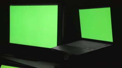 Tres-Monitores-En-Blanco-De-Diferentes-Tamaños-En-Un-Escritorio-En-Una-Habitación-Oscura-Con-Croma-De-Pantalla-Verde-Mostrado-Para-Fines-De-Composición