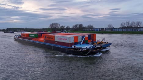 Frachtschiff-Beladen-Mit-Intermodalen-Containern-Navigieren-Auf-Dem-Fluss-Bei-Sonnenuntergang-In-Den-Niederlanden