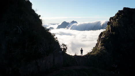 man-standing-in-mountain-top,-above-the-clouds,-overview-at-earth