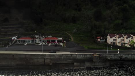 Toma-De-Drone-De-Un-Automóvil-Negro-Conduciendo-Por-Una-Carretera-Recta-Frente-A-La-Montaña