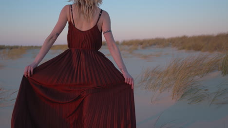 Woman-in-Red-Dress-Walks-on-Dunes,-Slow-Motion-Follow-from-Behind