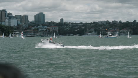 A-man-operates-a-small-boat-on-Sydney-Harbour,-leaving-a-wake-in-his-path