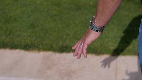 Close-up-on-the-hand-of-a-man-walking-next-to-a-stone-swimming-pool-in-Bali