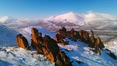 Rocas-En-Invierno-Tomadas-Desde-Un-Dron-En-Un-Clima-Soleado-Con-El-Telón-De-Fondo-De-Montañas-Y-Cielo-Azul-4k