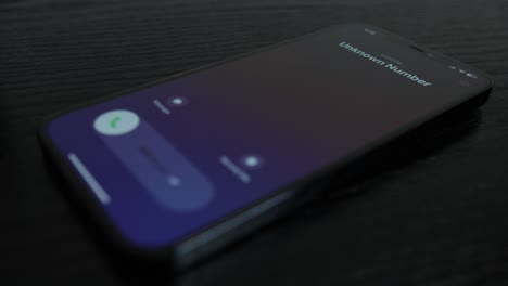 Close-up-shot-of-an-iPhone-receiving-a-call-from-an-unknown-number-on-black-wooden-table