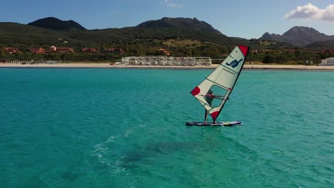 Disparo-De-Un-Dron-Pasando-Por-Windsurfistas,-Día-Soleado-De-Verano-En-Costa-Esmeralda,-Cerdeña,-Italia