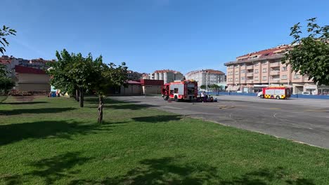 Los-Bomberos-Con-Sus-Camiones-En-El-Patio-Del-Colegio-Dan-Explicaciones-En-Una-Charla-A-Alumnos-Y-Profesores-En-El-Patio-Del-Colegio-En-Un-Día-Soleado-De-Verano,-Girando-Lentamente-A-La-Derecha