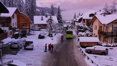 Luftaufnahme-Eines-Busses-Und-Von-Menschen-In-Einem-Skidorf,-Farbenfroher-Winterabend-In-Tirol,-Österreich---Neigung,-Drohnenaufnahme