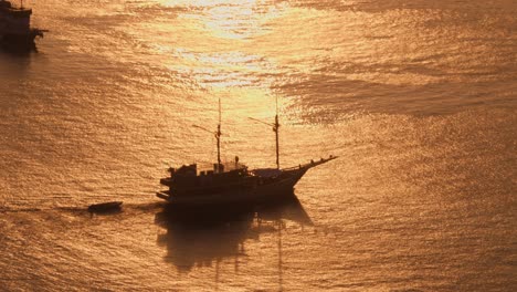 Luftaufnahme-Eines-Segelboots,-Das-Anmutig-über-Goldene-Gewässer-Vor-Dem-Hintergrund-Einer-Untergehenden-Sonne-Segelt