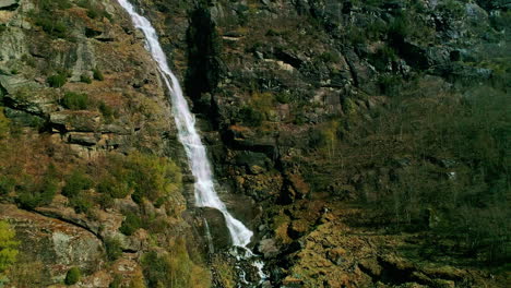 Waterfall-water-stream-by-mountainous-range,-aerial-drone-nature-shot