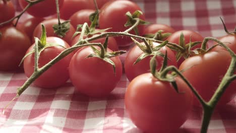 Closeup-shot-of-Cherry-tomatoes-fresh-clean-in-wooden-kitchen-table-knife-slow-motion-food-shot,-small-red-fruits-together-with-green-leaves