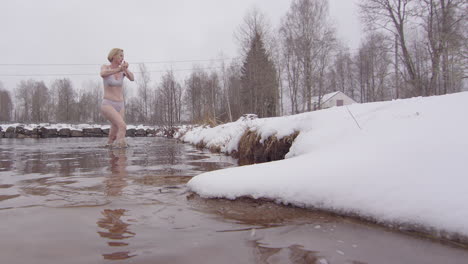 An-ice-bathing-woman-rings-out-her-gloves-as-she-exits-the-icy-water,-slowmo