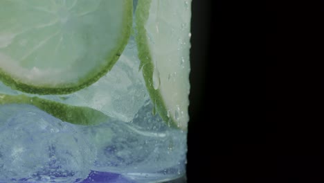Mit-Zitrone-Angereichertes-Eiskaltes-Getränk-In-Einem-Glas,-Vor-Einem-Eleganten-Schwarzen-Hintergrund
