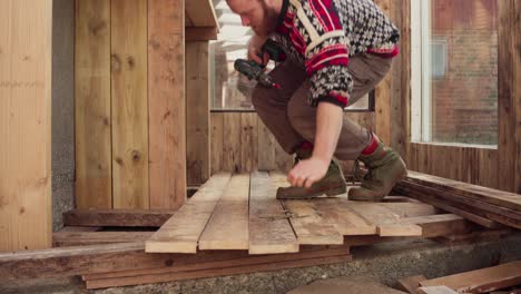 Portrait-Of-A-Handy-Man-Installing-Wood-Plank-Flooring-Using-Cordless-Screwdriver