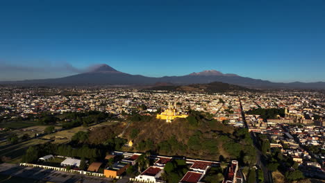 AERIAL:-Vibrant-church-on-the-Cholula-Pyramid,-sunny-evening-in-Puebla,-Mexico