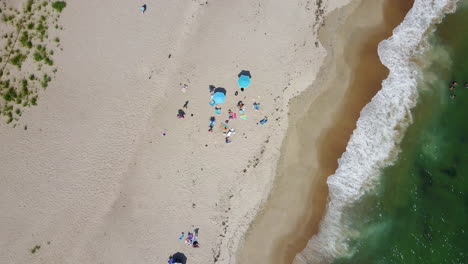 Drone-pointed-directly-down-showing-people-on-beach-and-waves