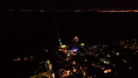 Aerial-view-of-the-city-at-night-with-fireworks-in-slow-motion-illuminating-the-sky