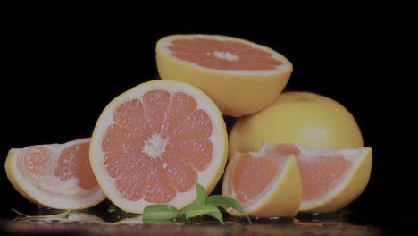 Slices-of-grapefruit-set-against-a-black-backdrop,-slowly-revolving,-embodying-the-concept-of-fresh-and-nourishing-food-and-drinks