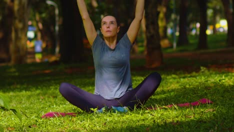 Serene-backdrop-of-trees-in-city-park,-woman-engaged-in-Yoga-exercises