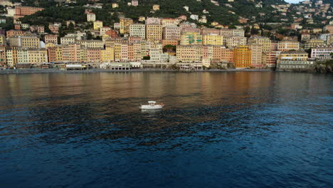 Aerial-view-away-from-a-boat-in-front-of-Camogli-city,-sunny-evening-in-Italy