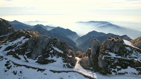 Explorador-Excursionista-Caminando-Por-Una-Montaña-Nevada-Con-Impresionantes-Vistas-De-La-Cordillera-De-Los-Alpes-Al-Fondo,-Resegone-En-Italia