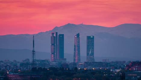 Timelapse-Del-Horizonte-De-Madrid-Con-5-Torres-área-De-Negocios-Ctba-Y-Picos-Nevados-De-La-Sierra-Como-Fondo-Atardecer-Día-A-Noche-Time-lapse