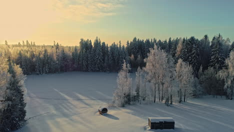 Remote-sauna-and-majestic-forest-landscape-in-winter-season,-aerial-view