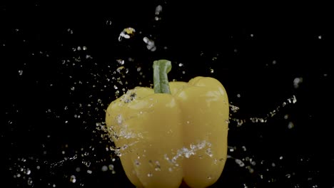 A-yellow-bell-pepper-spins-as-water-droplets-splash-against-it,-set-against-a-black-background,-representing-the-concept-of-freshness-and-vitality