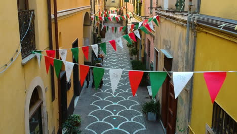 Drone-flying-backwards-in-middle-of-buildings,-over-a-narrow-alley-in-Italy