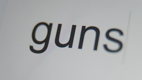 A-close-up-of-a-digital-screen-showing-a-text-cursor-and-"guns"-being-typed