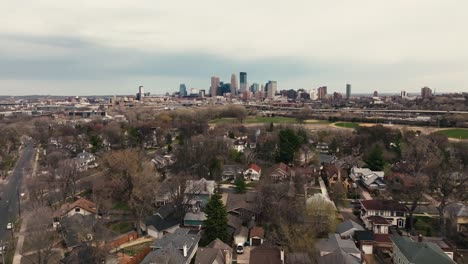 a-tilting-up-wide-aerial-drone-shot-of-the-Minneapolis-skyline-in-Minnesota-on-a-spring-day-with-suburban-homes-in-the-foreground