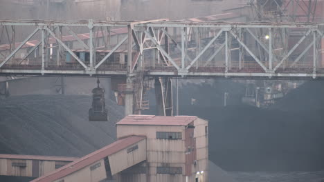 Heavy-machinery-operates-in-an-industrial-coal-yard-with-large-coal-piles-and-a-conveyor-structure
