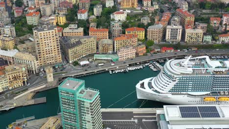 Aerial-view-overlooking-a-cruise-liner,-docked-at-the-port-of-Savona,-Italy---tracking,-drone-shot