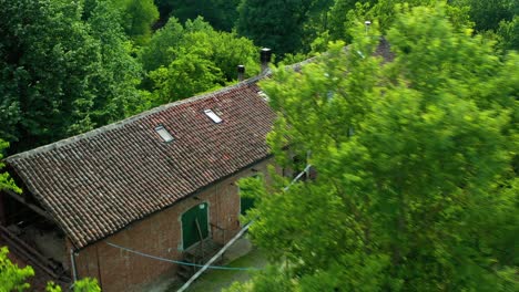 Aerial-view-over-a-winery-in-middle-of-trees-in-Piedmont,-Italy---circling,-drone-shot