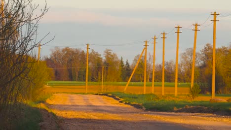 Empty-countryside-gravel-road-with-electricity-line-aside-during-golden-hour