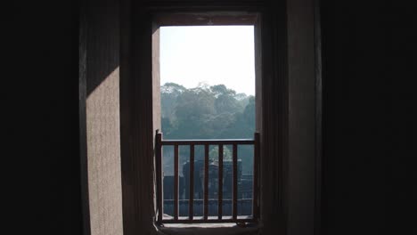 Mysterious-view-of-Angkor-Wat-through-an-ancient-window-at-sunrise,-silhouetted-frame