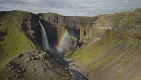 Aerial-footage-captures-powerful-Haifoss-waterfall-in-Iceland,-framed-by-a-captivating-rainbow